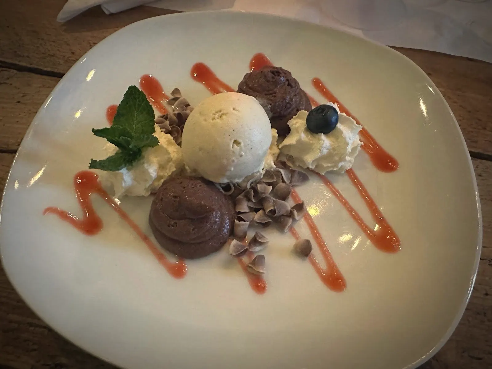 Dessert met bolletjes ijs, slagroom en een streep coulis
